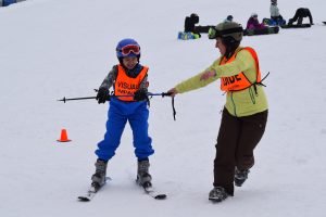 Athlete holding ski pole while volunteer guide directs 