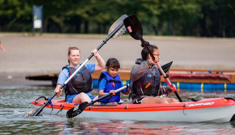 Youth athlete in a kayak between two guides.