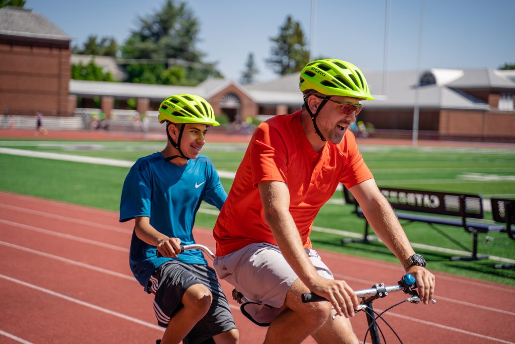 two men riding a tandem bicycle on a running track