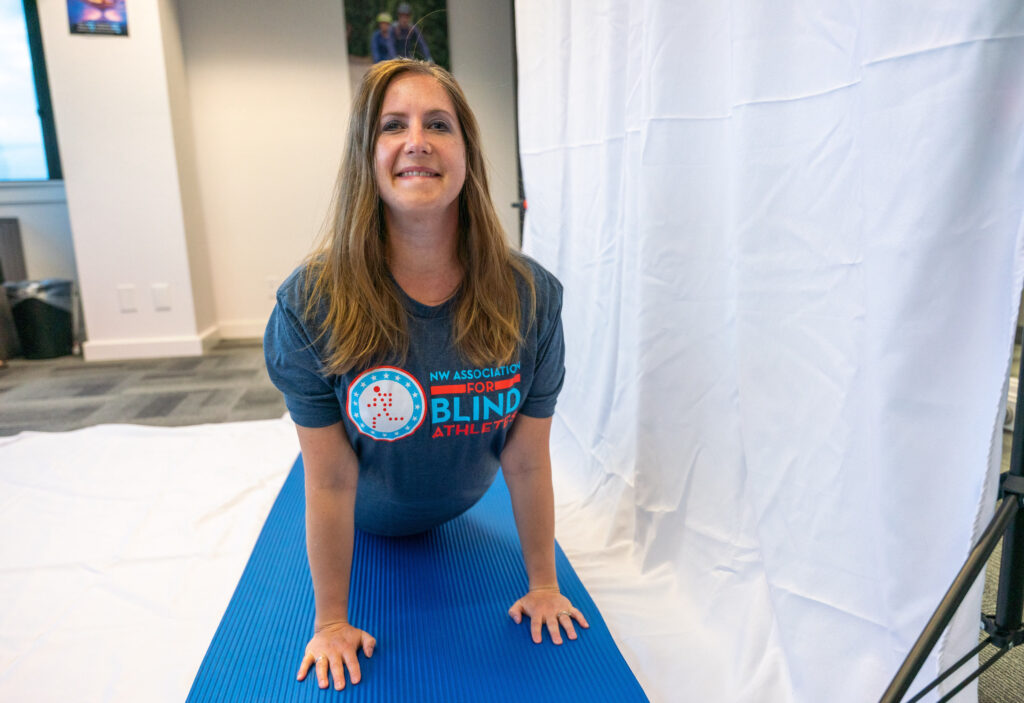 Female volunteer posing in up dog during a virtual yoga workout, wearing an NWABA tshirt.