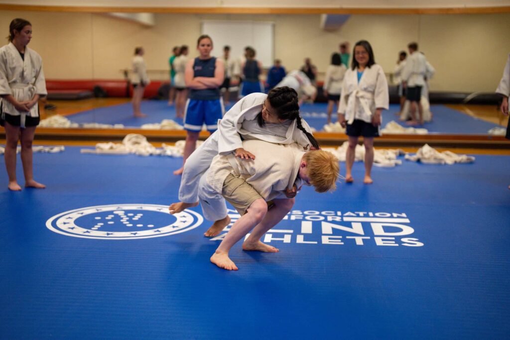 Young boy flips female counselor in a judo move.