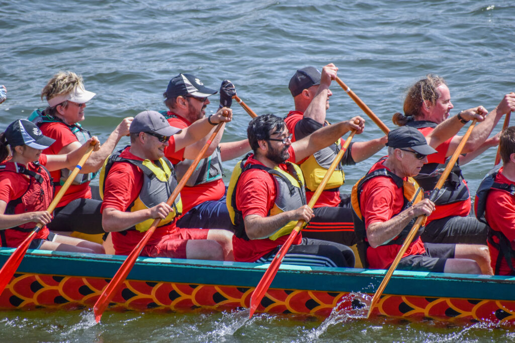 Group of people rowing in a dragon boat on the water.