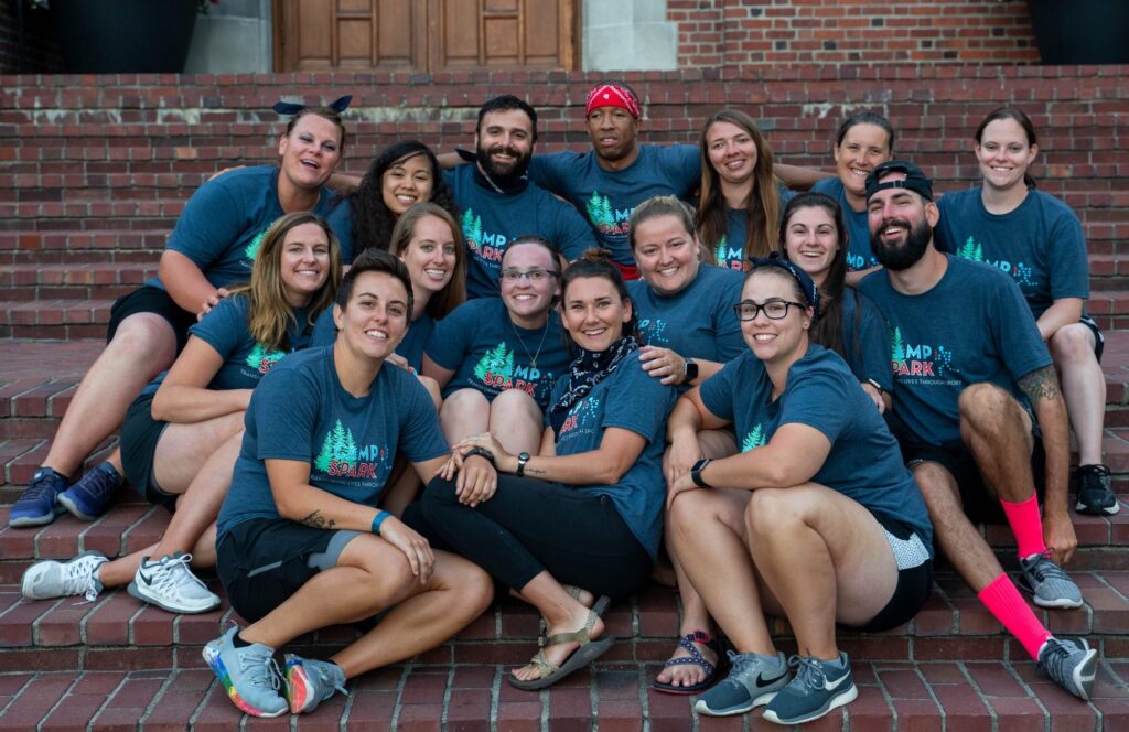 Group of Camp staff & counselors sitting on brick steps posing for the camera.