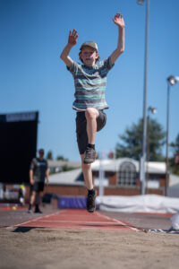 Young camper in the air during a high jump.