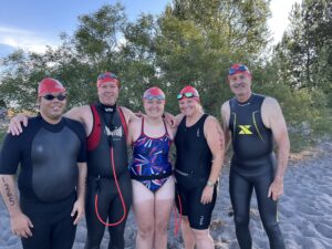 Five swimming athletes posing for a photo before getting into the lake.