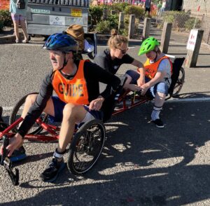 Athlete and guide transitioning to their recumbent bike at the triathlon.