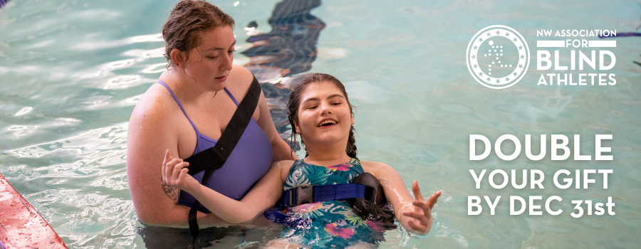 A young female camper with brown hair is floating in a pool being held by her female counselor.