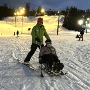 NWABA athlete, Suni, in a sit-ski being pushed from behind by a trained ski instructor.