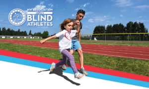 Young girl athlete is holding hands with her guide as they run across a track together. It's a sunny day with blue skies and grass in the background.