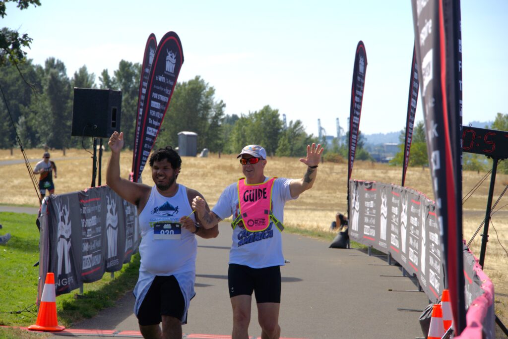 athlete and guide crossing the finish line at a race