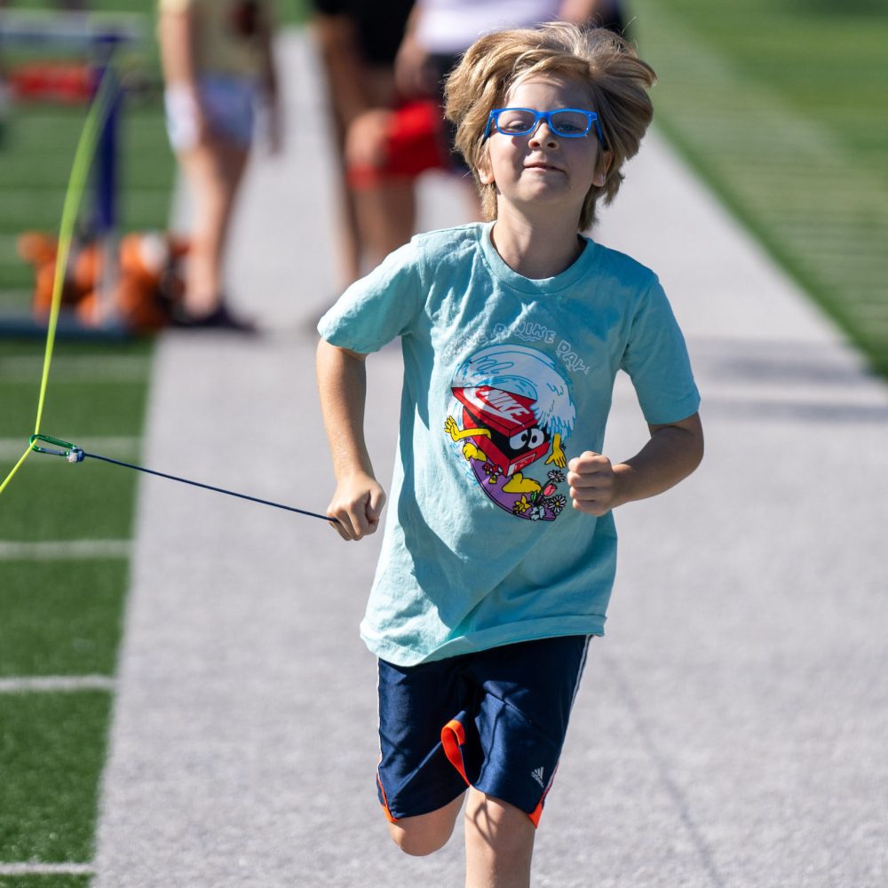 Young boy running towards camera with a tether.