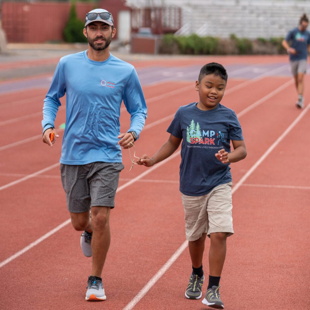 Young boy tethered to a guide running on a track.